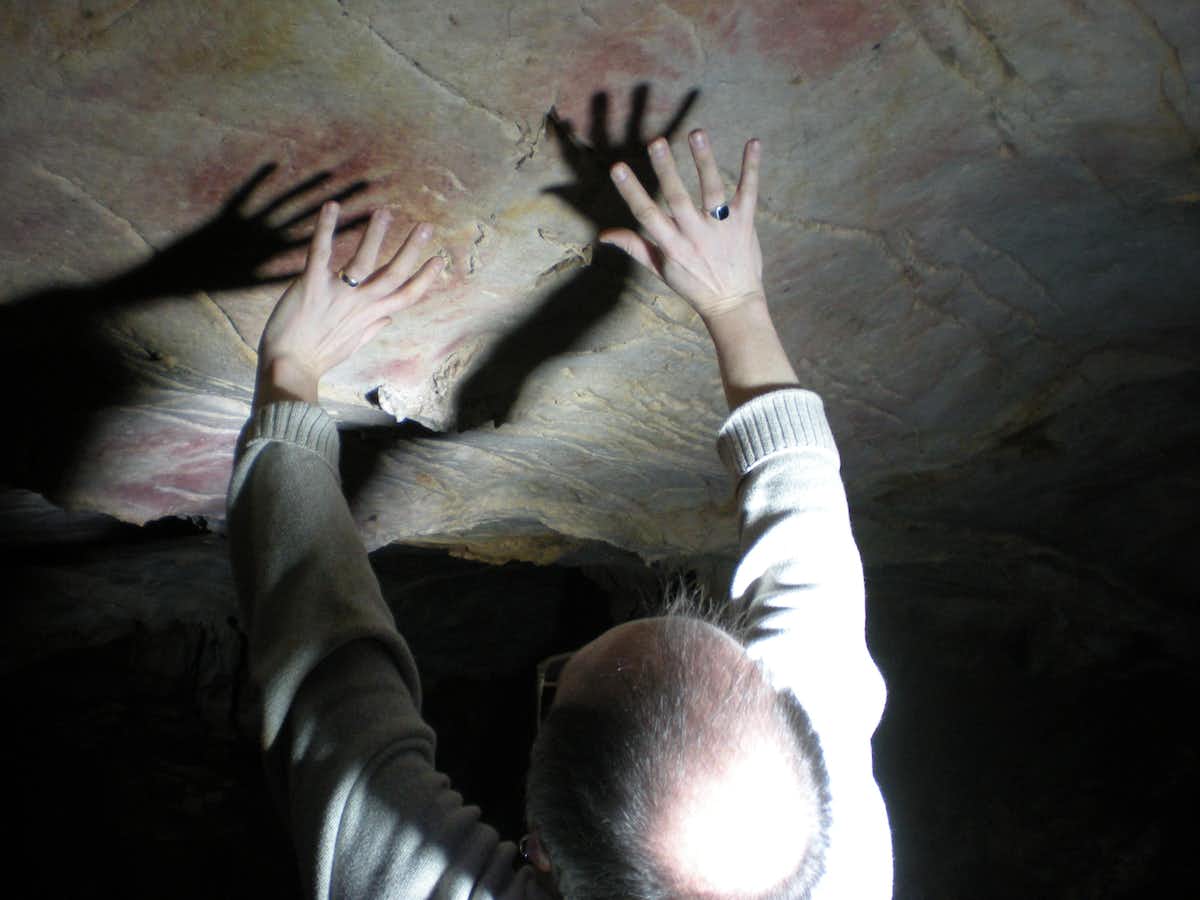 In many cases hand stencils were left on parts of cave walls and ceilings that were difficult to access, such as these in El Castillo cave, with Paul Pettitt showing the position of the hands.